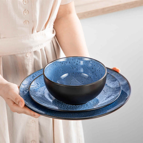 The Bubble 12-Piece Dinnerware Set features stoneware with a reactive glaze - offering farmhouse charm in blue plates and bowls - perfect for serving 4-vancasso